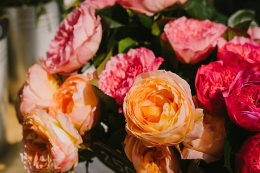 Sale of beautiful roses. Pink and orange roses. A vertical image. Flower market. Bouquet of flowers.