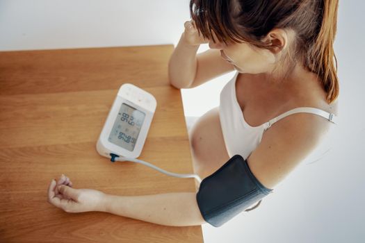 Pregnant woman measuring her blood pressure during the third trimester