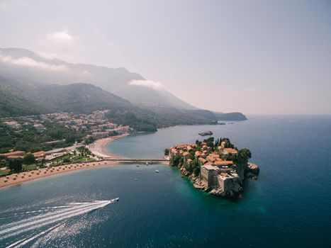 Yacht sails to the island of Sveti Stefan, leaving a foamy trail. High quality photo