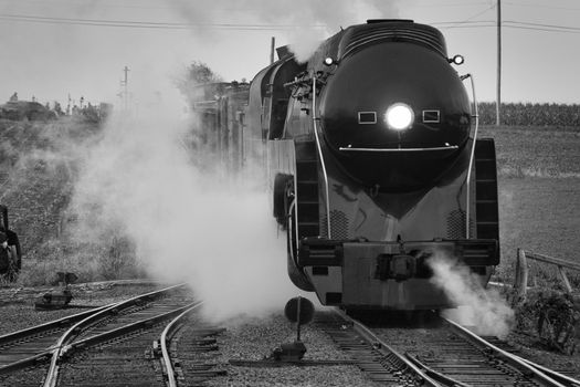 Black and White of An Antique Restored Steam Freight Train Approaching Head on Blowing Smoke and Steam