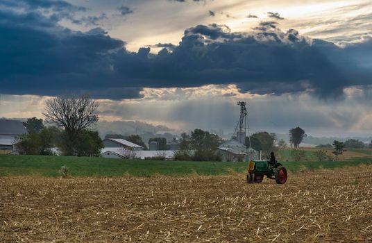 An Antique Farm Tractor Sitting in a Harvested Field Waiting, With a Person Looking Away