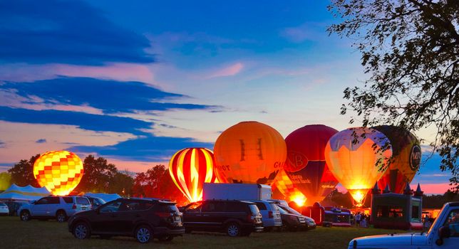 Multiple Hot Air Balloon Glow as Balloons Fire There Propane Tanks and Light Up the Balloons on a Summer Evening
