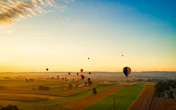 Aerial View of Many Hot Air Balloons In Flight Thru Rural Countryside On An Early Morning Balloon Festival