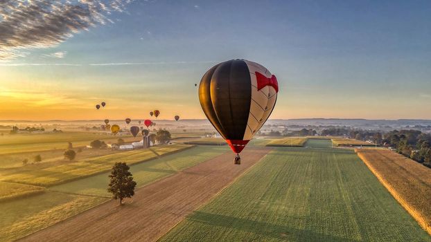 Bird in Hand, Pennsylvania, September 2019 - Aerial View of Many Hot Air Balloons In Flight Thru Rural Countryside On An Early Morning Balloon Festival