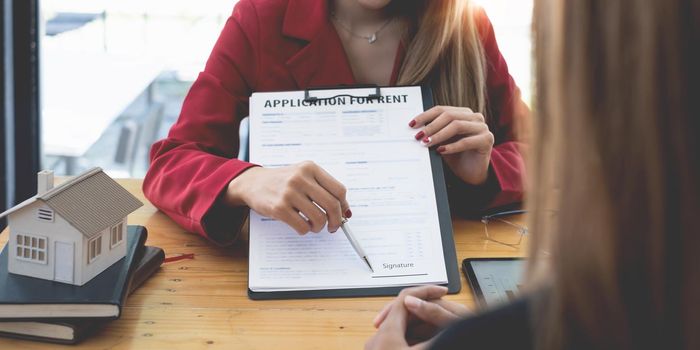 Close up of Business woman or agent pointing and signing agreement for buying house. Bank manager concept