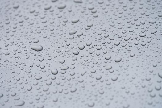 Small droplets of water on a matte gray background, close-up. Rain on a flat surface, condensation on glass