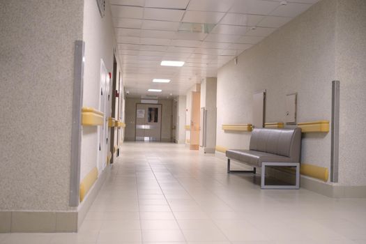 An empty gray corridor of an office building, nobody. Lighting on the hospital floor, intensive care. Hall of the clinic