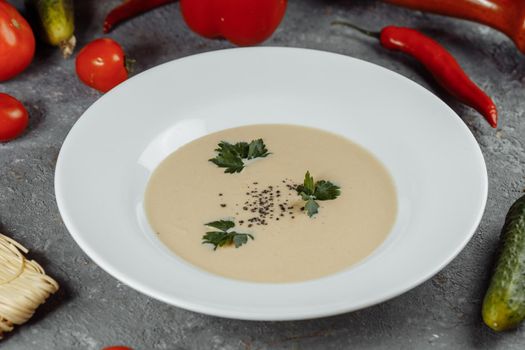 Cheese cream soup with sliced cheese and bread crumbs on a grey background.
