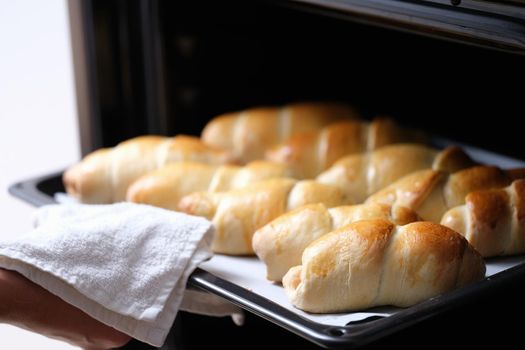 Open oven on a hot baking sheet, baked goods, close-up. Homemade croissants, puff pastry sausage, bun recipe