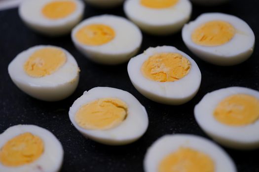 Set of halves of boiled chicken eggs on a black background, close-up. Chicken protein and yolk, organic food, keto diet