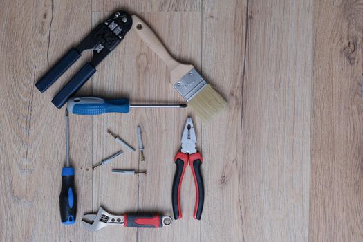 A set of tools for home renovation lies on the laminate. Adjustable wrench with screwdriver. Pasatizhi and paint brush.