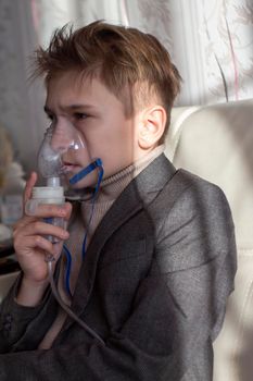 Little boy having inhalation for easing cough. Caucasian blonde boy inhales couples containing medication to stop coughing. Medical procedures. Inhaler. Respiratory medicine.