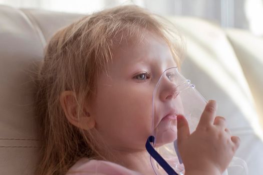 Little girl having inhalation for easing cough. Caucasian blonde girl inhales couples containing medication to stop coughing. Medical procedures. Inhaler. Respiratory medicine.