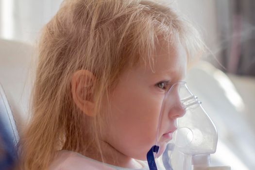 Little girl having inhalation for easing cough. Caucasian blonde girl inhales couples containing medication to stop coughing. Medical procedures. Inhaler. Respiratory medicine.