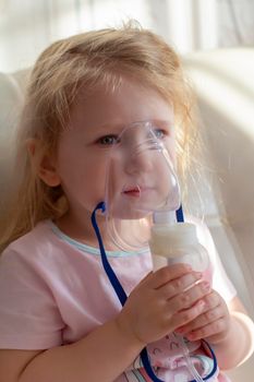 Little girl having inhalation for easing cough. Caucasian blonde girl inhales couples containing medication to stop coughing. Medical procedures. Inhaler. Respiratory medicine.