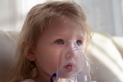 Little girl having inhalation for easing cough. Caucasian blonde girl inhales couples containing medication to stop coughing. Medical procedures. Inhaler. Respiratory medicine.