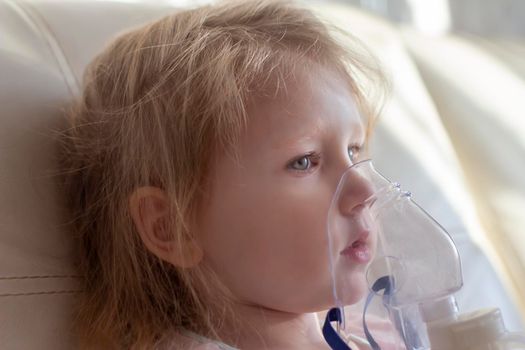 Little girl having inhalation for easing cough. Caucasian blonde girl inhales couples containing medication to stop coughing. Medical procedures. Inhaler. Respiratory medicine.