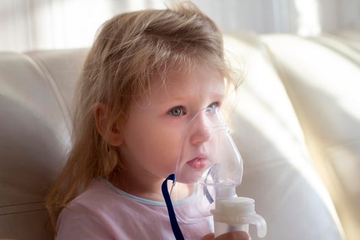 Little girl having inhalation for easing cough. Caucasian blonde girl inhales couples containing medication to stop coughing. Medical procedures. Inhaler. Respiratory medicine.