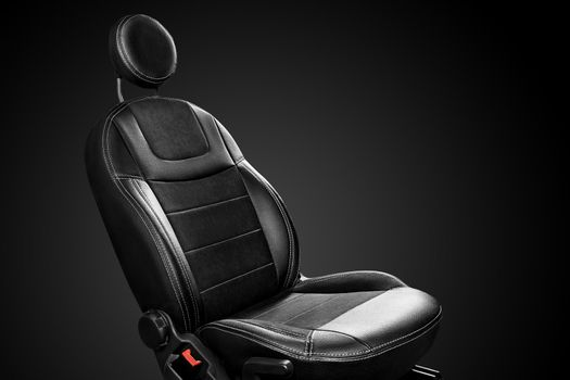 Modern ergonomic driver seat with round headrest made of eco-leather with suede inserts isolated on black background. Car interior detail