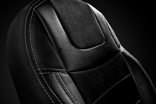 Closeup of comfortable ergonomic backrest of passenger car seat in black eco-leather with suede inserts on dark background