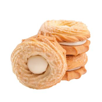 Delicate ring shaped butter shortbread sandwich biscuits with creamy filling sprinkled with sugar stacked isolated on white background