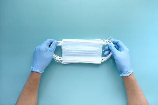 doctor hand in medical glove holding protective surgical face mask, close up .