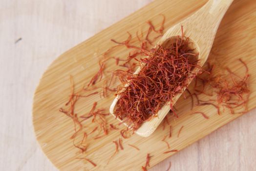Saffron Spice on a wooden spoon on table .