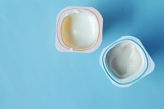 fresh yogurt in a plastic container on blue background .