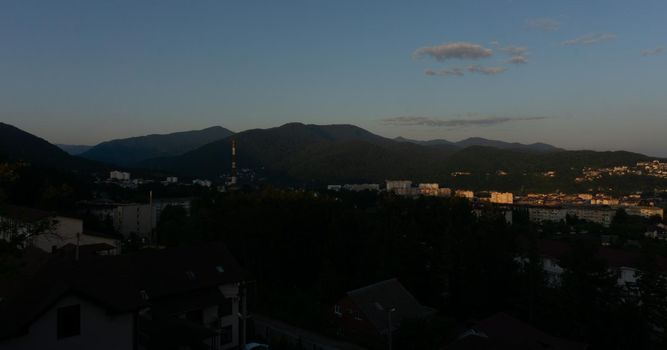 LAZAREVSKOE, SOCHI, RUSSIA - MAY, 27, 2021: Panorama of sunset in the mountains. A magical view of the sea and small town from the observation deck.