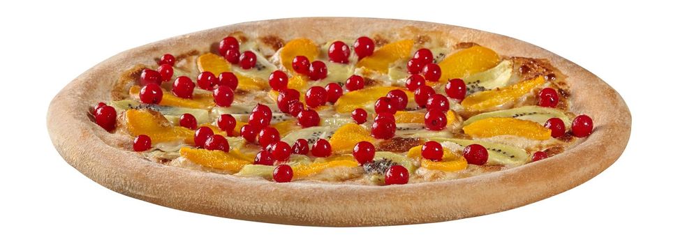 Closeup of appetizing light fruit pizza with cream cheese sauce and condensed milk topped with ripe peaches, kiwi and red currant berries isolated on white. Perfect tea treat for company