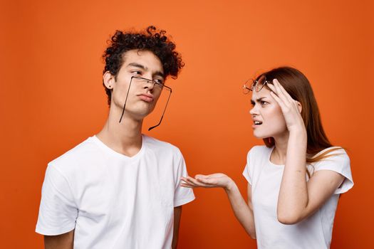 cheerful young couple in white t-shirts together friendship orange background. High quality photo