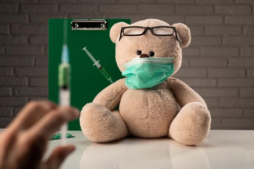 teddy bear in a medical mask with syringes in his shoulder , on the doctor 's desk