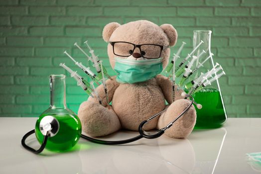 a teddy bear in a medical mask with syringes in his shoulder as a symbol of the research of vaccines and other drugs on animals or people