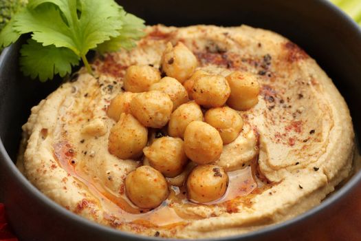 Closeup photo of tasty chickpeas hummus in black plate with smoked paprika. High quality photo