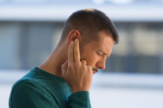 Man with tinnitus. Man touching his ear because of strong earache or ear pain. Otitis. High quality photo