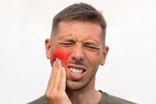 Man touching his cheek because of strong tooth pain with red highlighted area. Man suffering from toothache. Teeth problem. Man feeling tooth pain. High quality photo