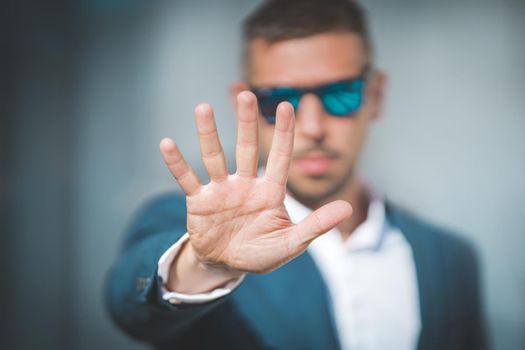 Bodyguard showing stop gesture with hand. Security guard blocks entrance. No entry. High quality photo