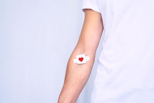 Blood donation. Blood donor with bandage after giving blood on a white background. Copy space. High quality photo
