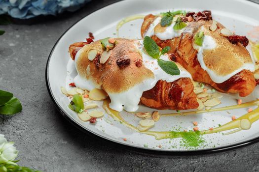 croissant with sweet cream and almonds on a plate. Delicious and healthy breakfast.