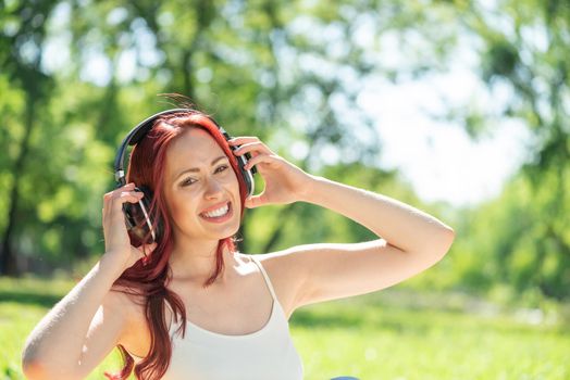 Young attractive woman listens to music in the park. Enjoying music in the park