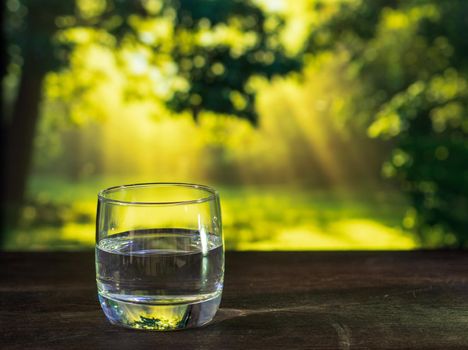 glass of water on wooden table bokeh background - vintage style picture