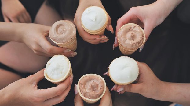 Girls friends join hands with ice cream in waffle cups in a circle