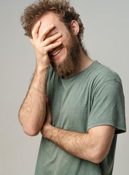 Cheerful Man in Gray T-shirt Laughing on White Background, Guy Enjoys Chatting, Nice Conversation, Positive Day. Close-up. High quality photo