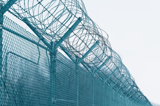 Barbed wire. Security measures for prisoners in prison. Prison fence against blue sky.