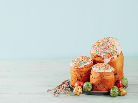Traditional Russian Ukrainian Easter Cake Kulich. Orthodox Christian Easter Bread or Easter Cake with frosting, Easter Eggs and willow twigs on blue background. Copy space for text, place for design
