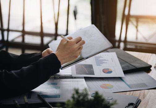 Electronic work concept, female employee is using tablet and ducument to analyze company profits to improve revenue over last year