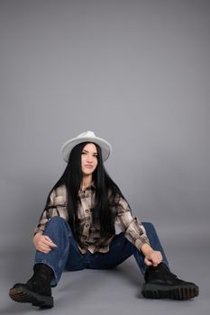 portrait of beautiful young woman in brown checkered shirt and jeans on gray background. pretty female portrait.