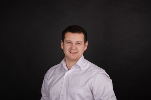 portrait of a handsome man in a white shirt on a black background. business style, office wear. businessman.