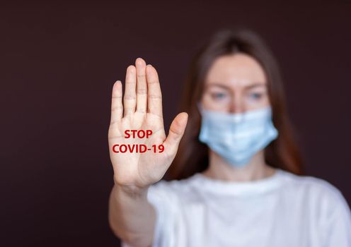 Coronavirus concept. Girl wearing mask for protection from disease and show stop hands gesture for stop corona virus outbreak. Global call to stay home. Stop the pandemic with vaccination