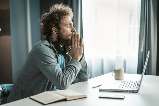 Aspiring Entrepreneur Sits at Work Desk in his Office. There is a Laptop, Notebook, Phone and a Cup on the Table. Time to Make a Decision. Close-up. Copy Space. High quality photo